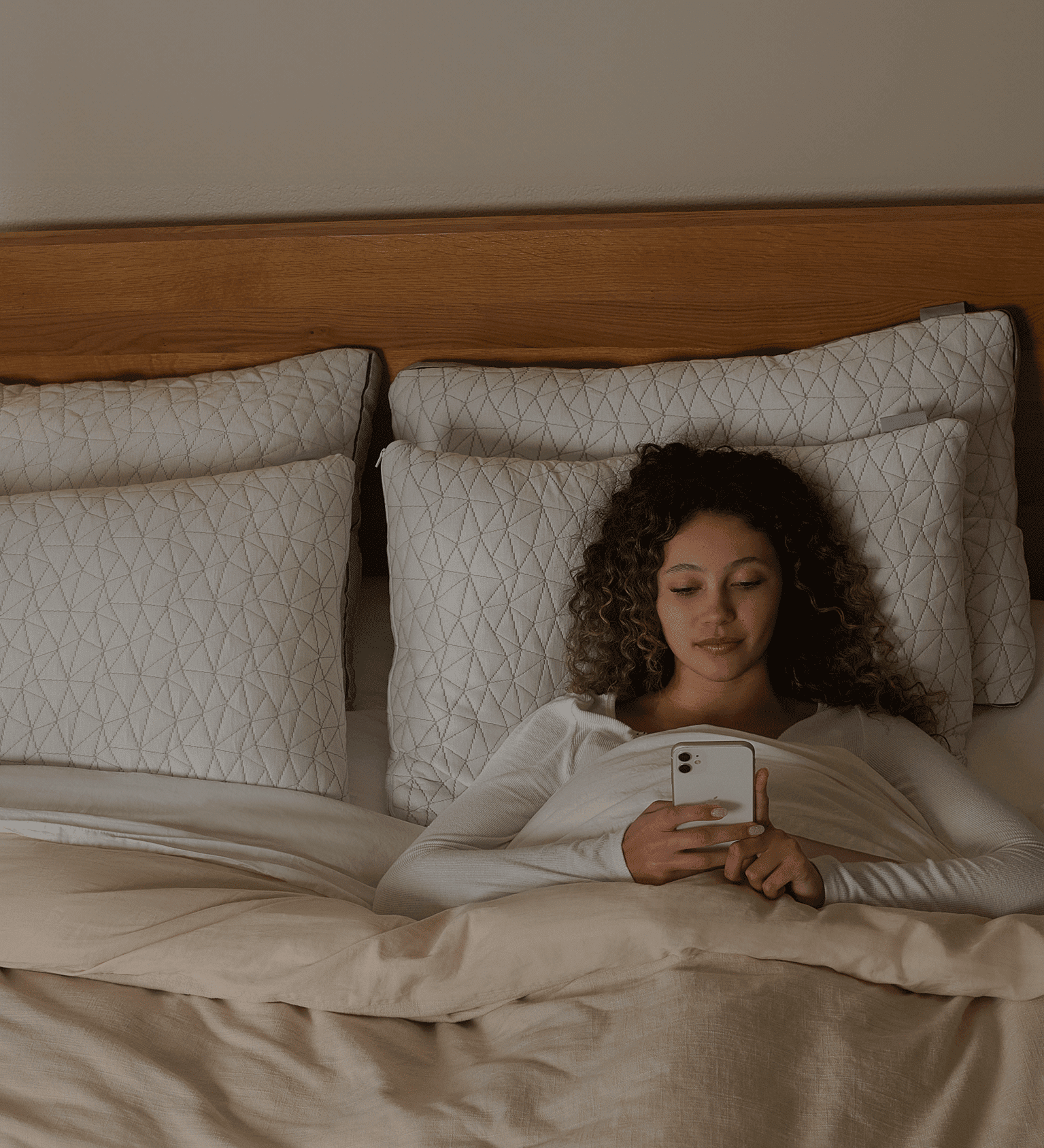 Woman under a blanket looking at a phone